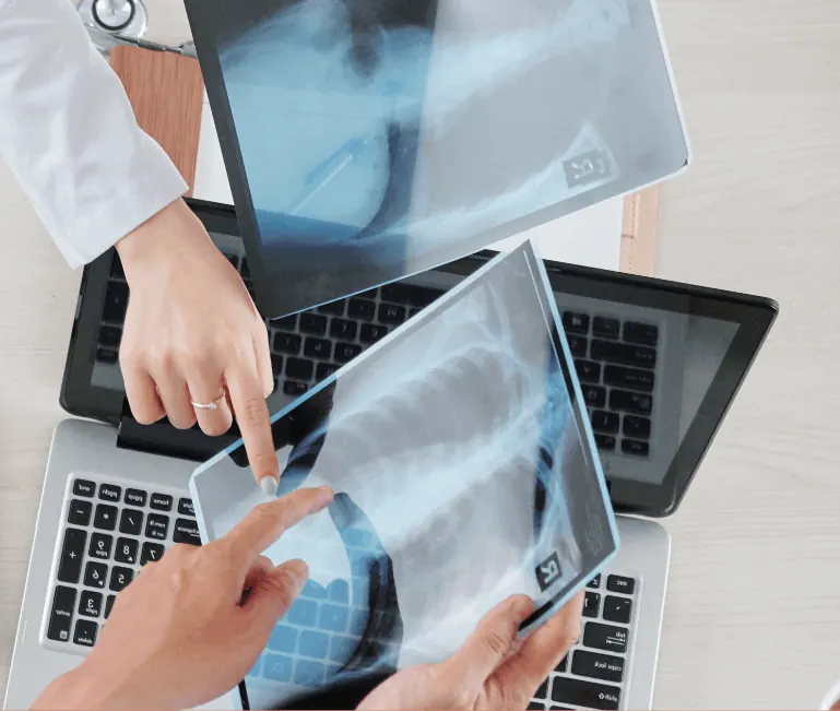 Doctors discussing X-rays on a tablet and laptop